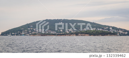 Explore the tranquil beauty of Prince Islands during a serene evening on the water with lush greenery and charming homes lining the coastline 132339462