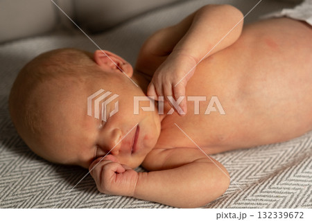 Sleepy baby resting peacefully on a soft blanket in a cozy indoor space during the day 132339672