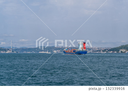 Container ship navigating through the Bosphorus Strait with city skyline in the background on a clear day 132339916