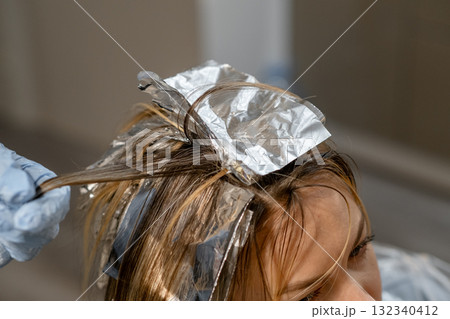 Professional hair coloring process with foils applied in a salon setting during daylight hours Professional hair coloring process with foils applied in a salon setting during daylight hours 132340412
