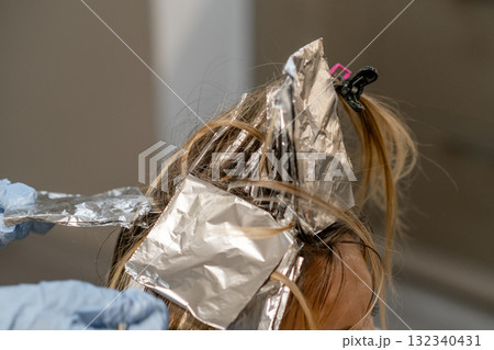 Hair coloring process in a salon with foils applied for highlighting effects 132340431