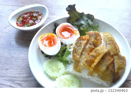 deep fried slice gourami fish topping plain rice with soft boiled egg and fresh vegetable on plate dipping spicy sweet fish sauce deep fried slice gourami fish topping plain rice with soft boiled egg and fresh vegetable on plate dipping spicy sweet fish sauce 132340463
