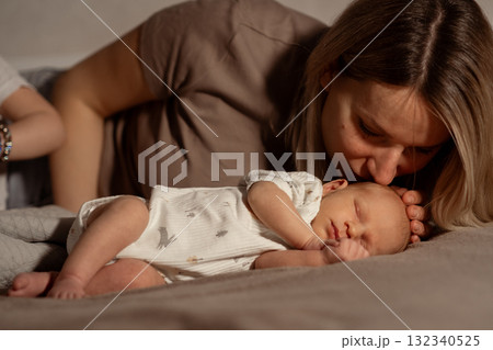 Mom cuddles her sleeping baby on a cozy bed during a quiet afternoon at home, sharing a tender moment of love and connection 132340525