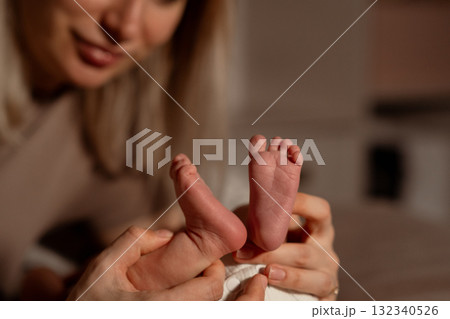 Mom gently holds her babys tiny feet during a cozy moment at home in the evening Mom gently holds her babys tiny feet during a cozy moment at home in the evening 132340526