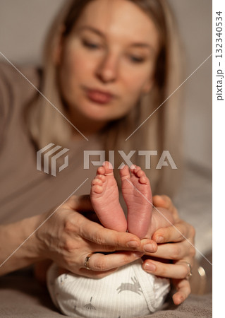 Mom gently holds her newborn babys tiny feet in a cozy indoor setting during a quiet moment of bonding in the afternoon light Mom gently holds her newborn babys tiny feet in a cozy indoor setting during a quiet moment of bonding in the afternoon light 132340534