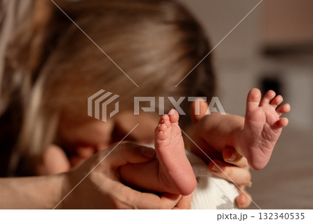 Tender moment between mother and baby with soft focus on tiny feet during a cozy indoor setting in the evening 132340535