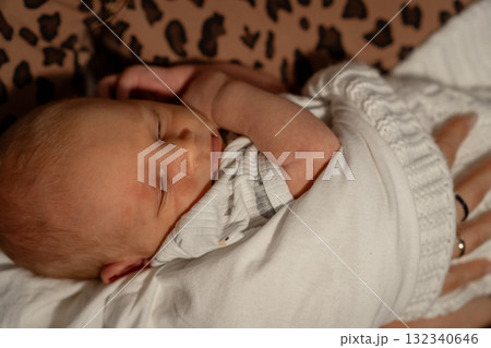 Mom gently cradles her sleeping baby in a cozy setting, showcasing a tender moment of bonding and warmth during an evening at home 132340646