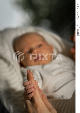 Mom cradles her newborn baby while enjoying a peaceful moment in a serene outdoor setting during golden hour Mom cradles her newborn baby while enjoying a peaceful moment in a serene outdoor setting during golden hour 132340647