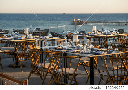 Stunning oceanfront dining scene with elegantly set tables and glassware 132340932