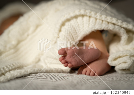 Cozy baby feet peeking out from a knitted blanket during a quiet afternoon at home Cozy baby feet peeking out from a knitted blanket during a quiet afternoon at home 132340943