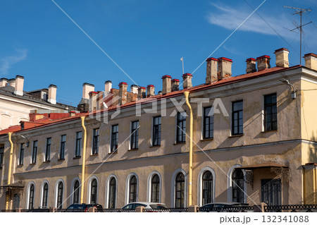 Historic architecture of Saint Petersburg with yellow facade and red roofs against a clear blue sky 132341088