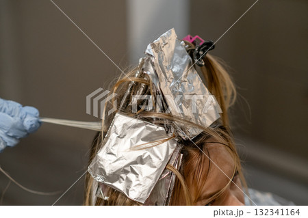 Hair coloring process in a salon with foil highlighting techniques during daytime Hair coloring process in a salon with foil highlighting techniques during daytime 132341164