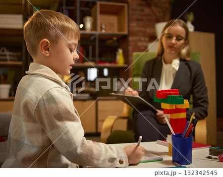 Boy drawing and playing with psychologist during emotional development session 132342545