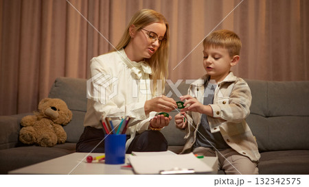 Child psychologist using number cards for therapy exercise with boy in cozy office 132342575