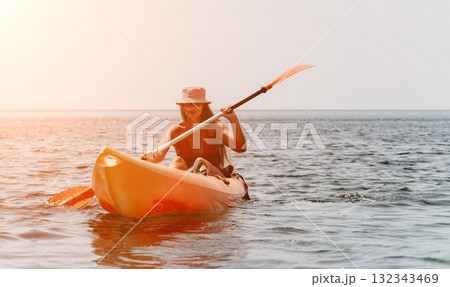 Kayaking Woman Ocean Sunset - A woman paddles a kayak on the ocean at sunset. 132343469