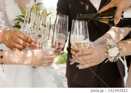 Elegant Wedding Champagne Toast: Celebrating Couple with Sparkling Wine Glasses, Outdoor Reception, Warm Sunlight, Ivory and Brown Tones, Joyful Moment. 132343922
