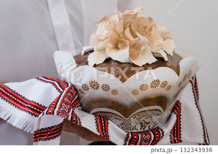 Traditional Ukrainian Easter Bread Paska with Floral Decorations Held in Hands, White Shirt, Red Embroidery, Festive Spring Holiday Still Life. 132343936