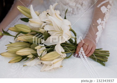 Elegant White Lily Bridal Bouquet Held by a Bride in Lace Wedding Dress, Romantic Floral Arrangement, Close-Up, Soft Focus Photography 132343937