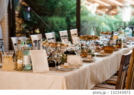 Elegant Wedding Reception Table Setting with Food, Wine, and Lush Garden View. Cream Linen, Glassware, and Fine Dining Atmosphere Elegant Wedding Reception Table Setting with Food, Wine, and Lush Garden View. Cream Linen, Glassware, and Fine Dining Atmosphere 132343972