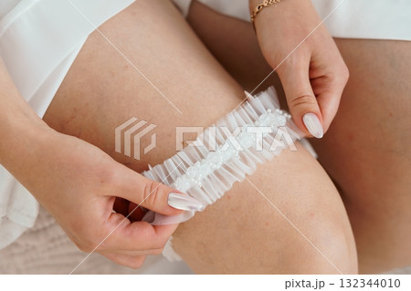 Bridal Garter Application: Close-Up of White Lace Legwear with Pearl Embellishments, Wedding Preparation, Delicate Texture, Soft Lighting. Bridal Garter Application: Close-Up of White Lace Legwear with Pearl Embellishments, Wedding Preparation, Delicate Texture, Soft Lighting. 132344010