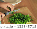hands cutting green spring onion on cutting board for cooking 132345718