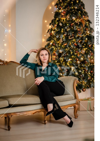 Woman Relaxing on Sofa by Christmas Tree at Home 132346214