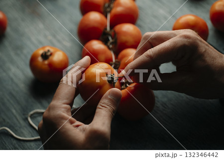 man threading tomates de colgar together 132346442