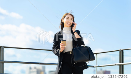 スマートフォンで話す笑顔の女性・ビジネスウーマン スマートフォンで話す笑顔の女性・ビジネスウーマン 132347291