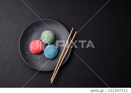 Japanese mochi, ice cream or Asian sweets with fruit filling. Mochi of different colors Japanese mochi, ice cream or Asian sweets with fruit filling. Mochi of different colors 132347312