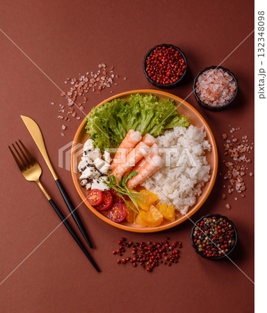 Bowl with shrimps, seafood, rice, oranges, tomatoes with sauce. Bowl with prawns 132348098