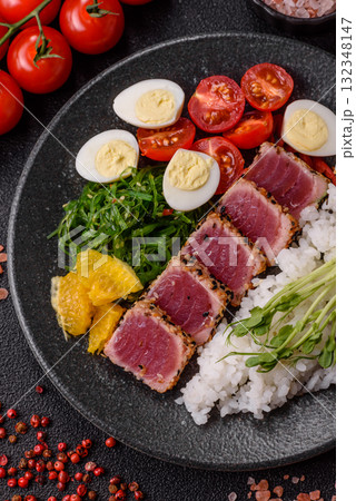 Seafood bowl, tuna tataki fillet slices with rice, oranges, tomatoes and sauce. Tuna bowl Seafood bowl, tuna tataki fillet slices with rice, oranges, tomatoes and sauce. Tuna bowl 132348147