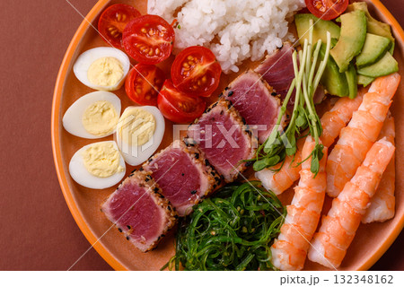 Seafood bowl, tuna tataki fillet slices with rice, oranges, tomatoes and sauce. Tuna bowl Seafood bowl, tuna tataki fillet slices with rice, oranges, tomatoes and sauce. Tuna bowl 132348162