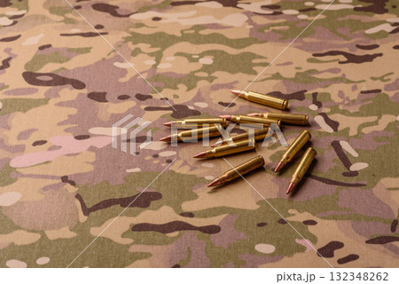 Machine gun cartridges on a camouflage background, military wallpaper. Camouflage background Machine gun cartridges on a camouflage background, military wallpaper. Camouflage background 132348262