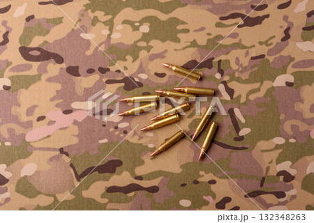 Machine gun cartridges on a camouflage background, military wallpaper. Camouflage background Machine gun cartridges on a camouflage background, military wallpaper. Camouflage background 132348263