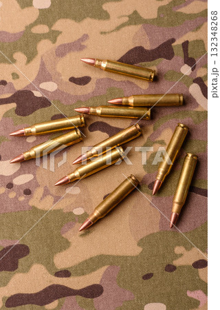 Machine gun cartridges on a camouflage background, military wallpaper. Camouflage background Machine gun cartridges on a camouflage background, military wallpaper. Camouflage background 132348268