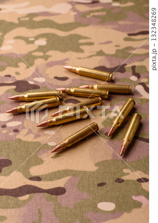 Machine gun cartridges on a camouflage background, military wallpaper. Camouflage background Machine gun cartridges on a camouflage background, military wallpaper. Camouflage background 132348269