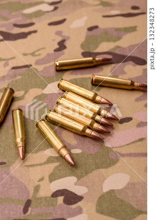Machine gun cartridges on a camouflage background, military wallpaper. Camouflage background 132348273