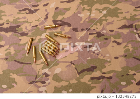 Machine gun cartridges on a camouflage background, military wallpaper. Camouflage background 132348275