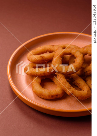 Onion rings or fried squid in breadcrumbs with sauce, takeaway food. Onion rings fried 132348914