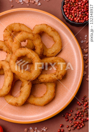Onion rings or fried squid in breadcrumbs with sauce, takeaway food. Onion rings fried 132348917