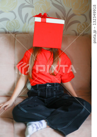 A girl in a red T-shirt and a gift box on her head. Girl - Christmas gift 132349918