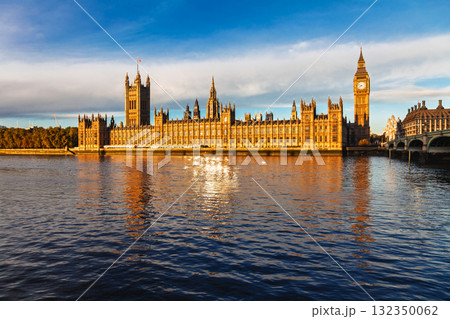 Golden sunlight illuminating the Palace of Westminster and Big Ben reflected in the River Thames in London 132350062