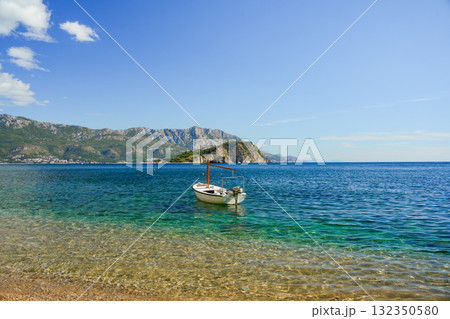 Beautiful clear blue sea with small boat near the coast and Hawaii Island in the distance, Budva, Montenegro. 132350580