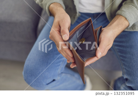 Man who is experiencing a financial crisis opens his wallet with a single coin inside 132351095