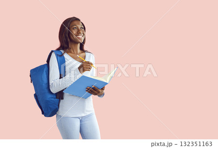 Happy smiling girl holding notebook with backpack and writing on pink background. Happy smiling girl holding notebook with backpack and writing on pink background. 132351163