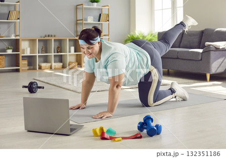 Happy overweight woman using laptop and doing sports workout with remote fitness trainer 132351186