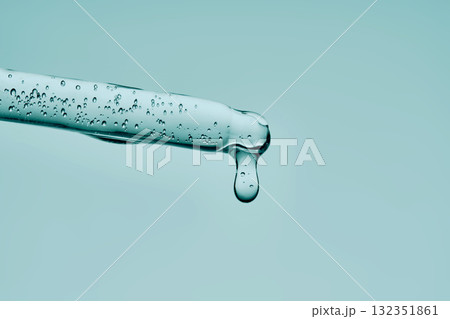 The texture of a serum with bubbles dripping from a pipette on a mint background. 132351861