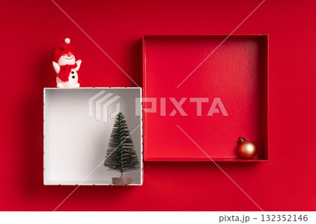 Festive red flat lay with two square box frames, a snowman and a tiny tree. Large copy space inside and around for text and mockups great for banners, headers, showcases and retail displays. 132352146