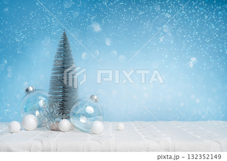 Light winter background: small tree and glass baubles on snowy surface, gentle blue bokeh and large copy space. Clean minimal look for banners, headers, posters and greetings. 132352149
