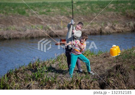 Funny fishing. Two of the boy's friends hooked an old shoe with a fishing rod and are laughing. Funny fishing. Two of the boy's friends hooked an old shoe with a fishing rod and are laughing. 132352185